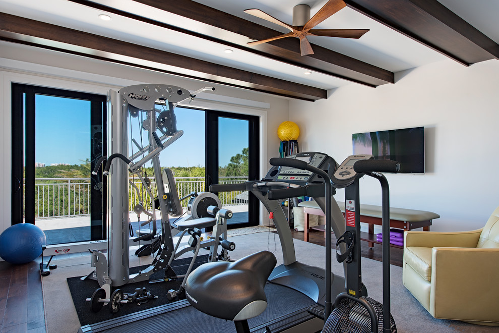 Classic multi-use home gym in Miami with white walls, dark hardwood flooring and brown floors.