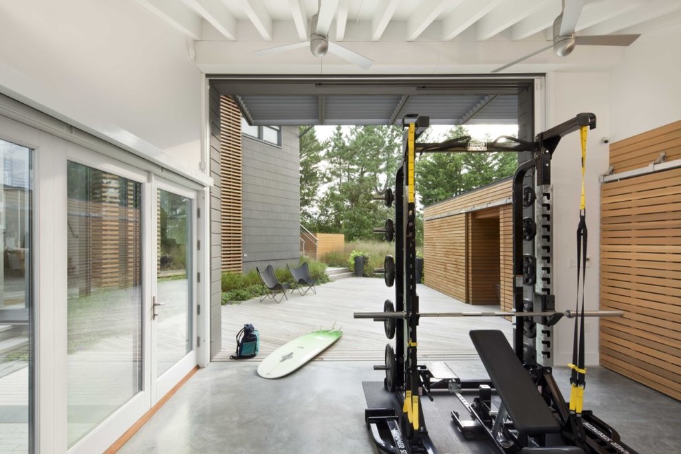 Cette image montre une salle de sport marine avec sol en béton ciré, un mur blanc et un sol gris.