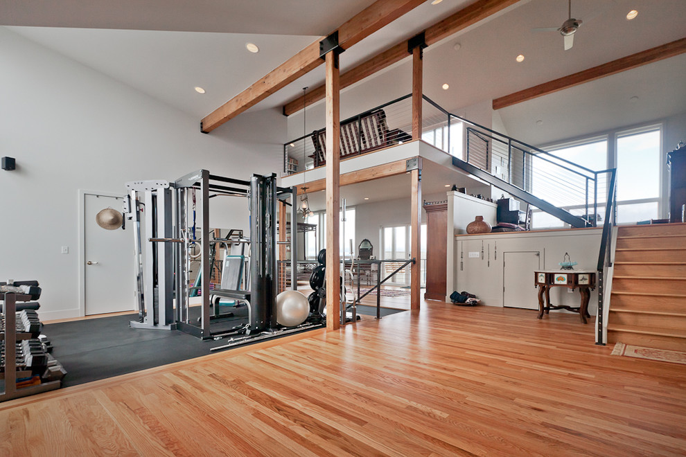Exemple d'une grande salle de musculation tendance avec un mur blanc et un sol en bois brun.