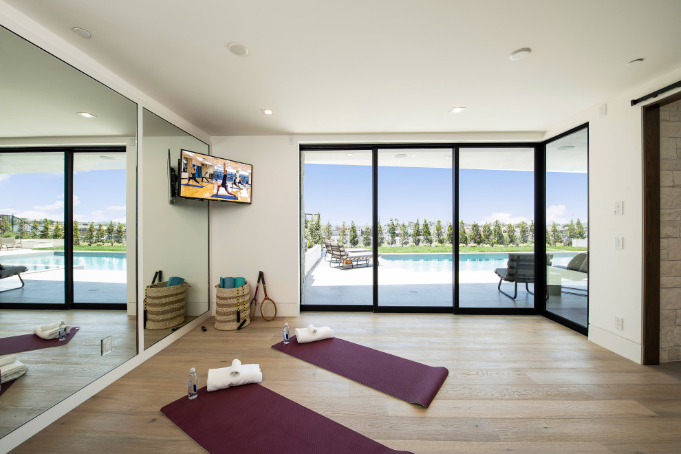 Mittelgroßer Klassischer Yogaraum mit weißer Wandfarbe, hellem Holzboden und beigem Boden in Orange County