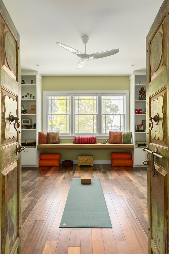Réalisation d'un petit studio de yoga design avec un mur vert, un sol en bois brun et un sol marron.