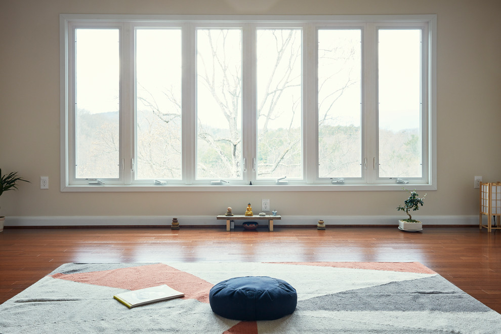 Foto de estudio de yoga moderno pequeño con paredes blancas, suelo de madera en tonos medios y suelo marrón