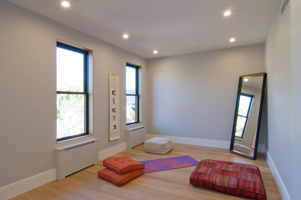 Mittelgroßer Asiatischer Fitnessraum mit grauer Wandfarbe, hellem Holzboden und braunem Boden in New York