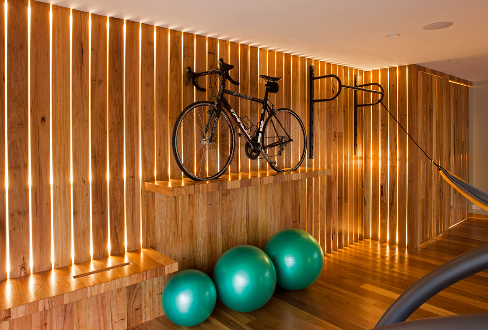Idée de décoration pour une salle de sport design multi-usage et de taille moyenne avec un mur marron, un sol en bois brun et un sol marron.