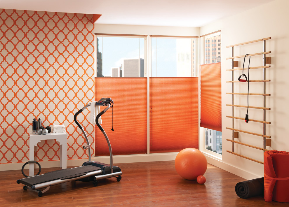 Large contemporary multi-use home gym in Other with orange walls, medium hardwood flooring and orange floors.