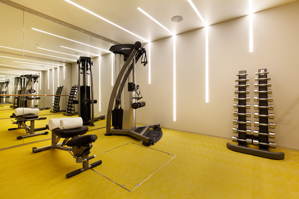 Medium sized contemporary home gym in London with grey walls and yellow floors.