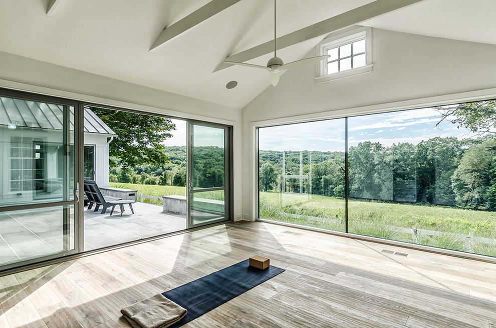 Mid-sized country light wood floor home yoga studio photo in New York with white walls