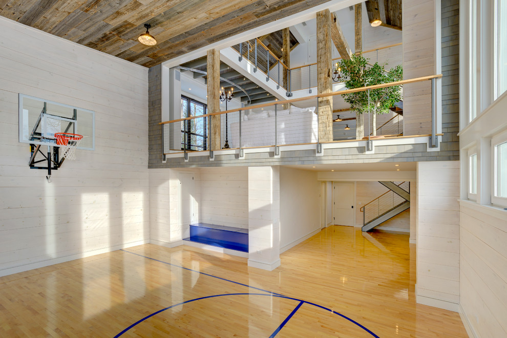 This is an example of an expansive farmhouse indoor sports court in Bridgeport with white walls and light hardwood flooring.