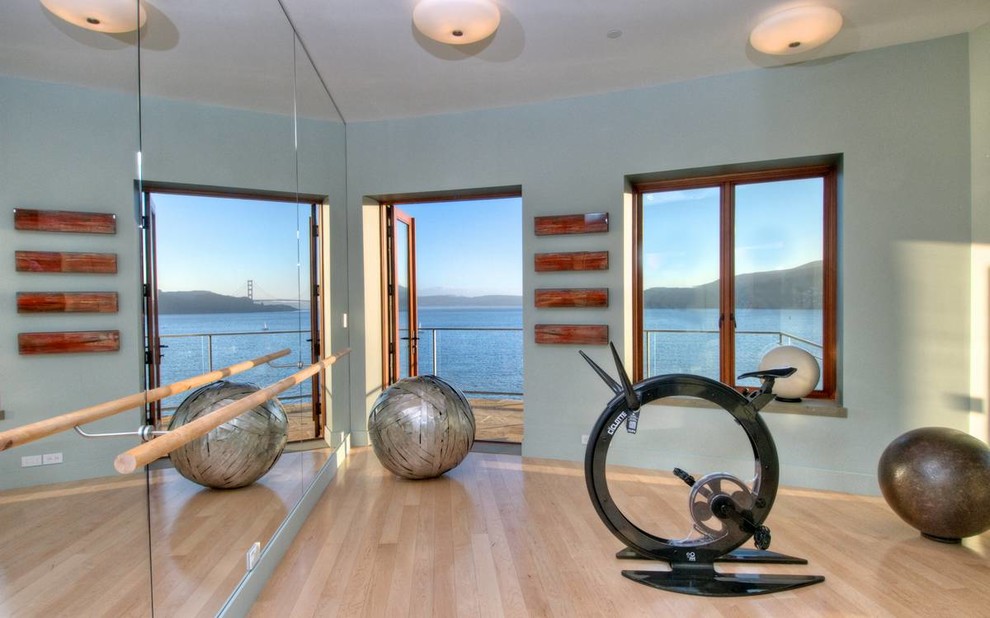 Contemporary home gym in San Francisco with blue walls, light hardwood flooring and feature lighting.