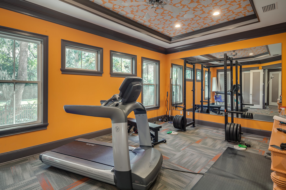 Foto di una sala pesi eclettica di medie dimensioni con pareti arancioni e moquette