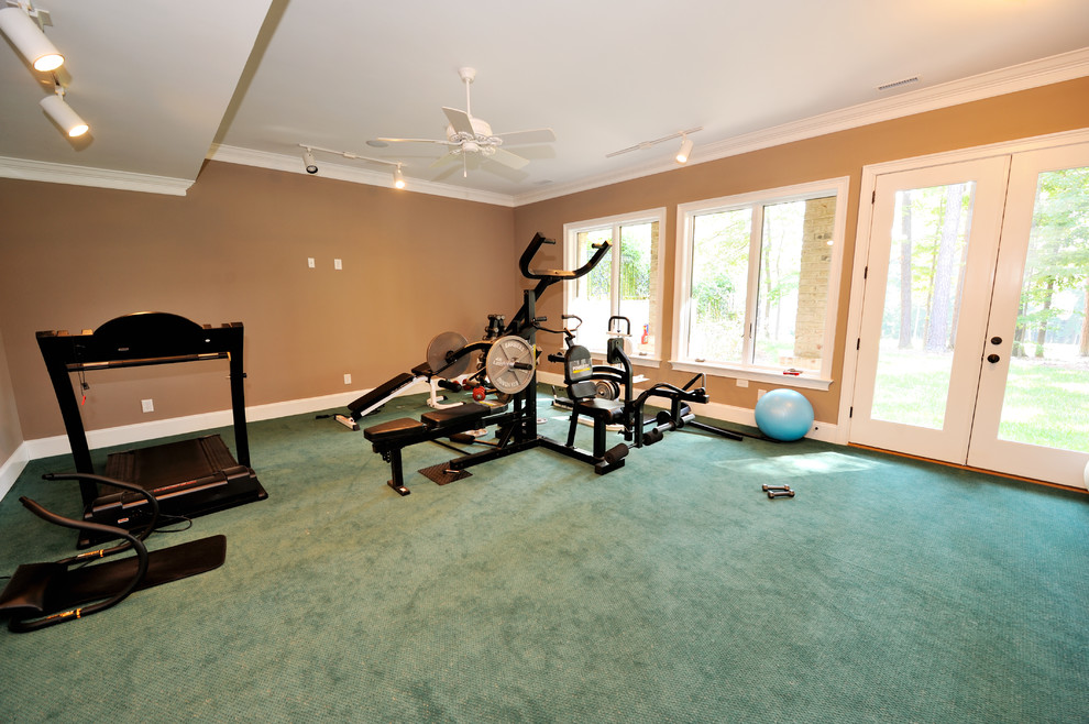 Medium sized multi-use home gym in Raleigh with brown walls, carpet and green floors.