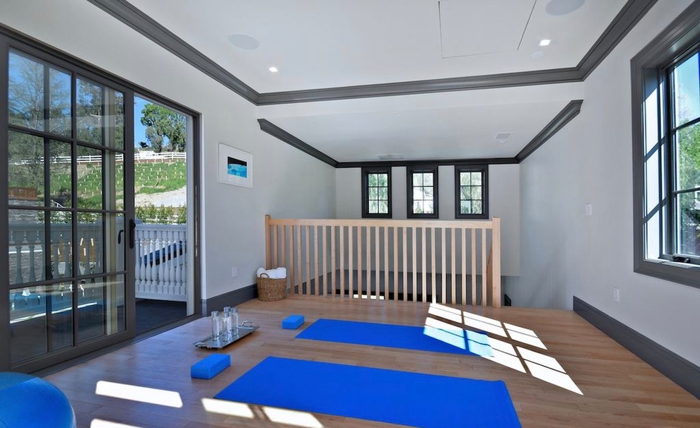 Immagine di uno studio yoga tradizionale di medie dimensioni con pareti bianche, parquet chiaro e pavimento marrone