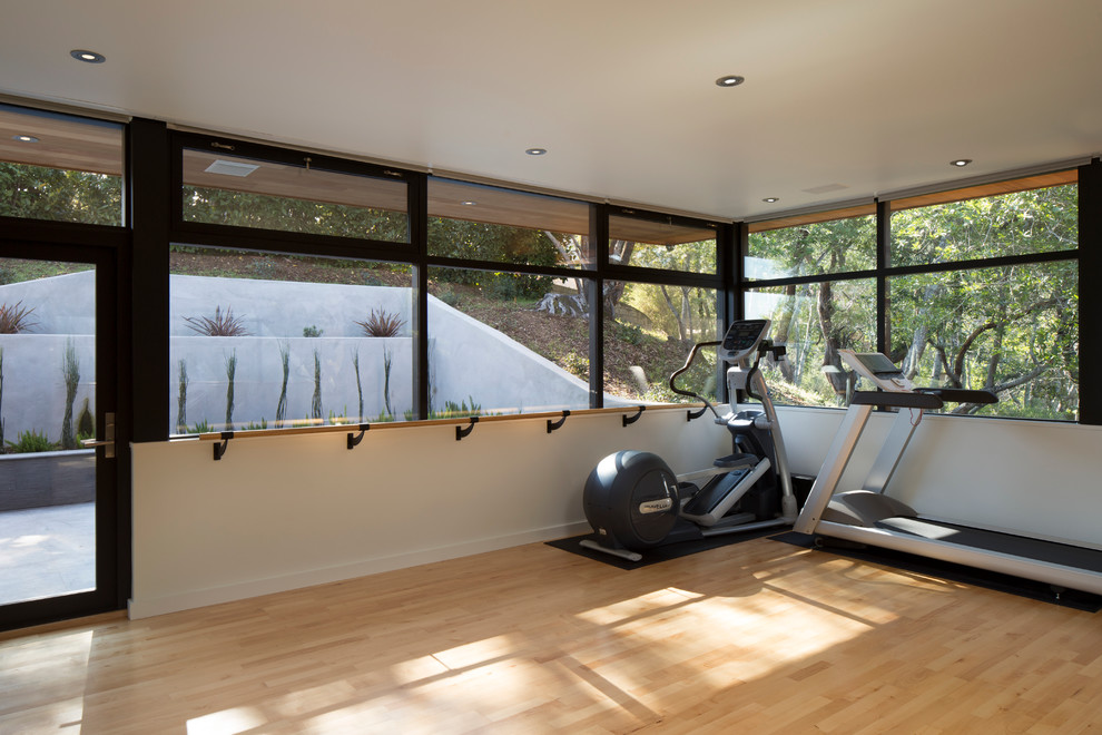 Multiuse home gym - contemporary light wood floor multiuse home gym idea in San Francisco with white walls