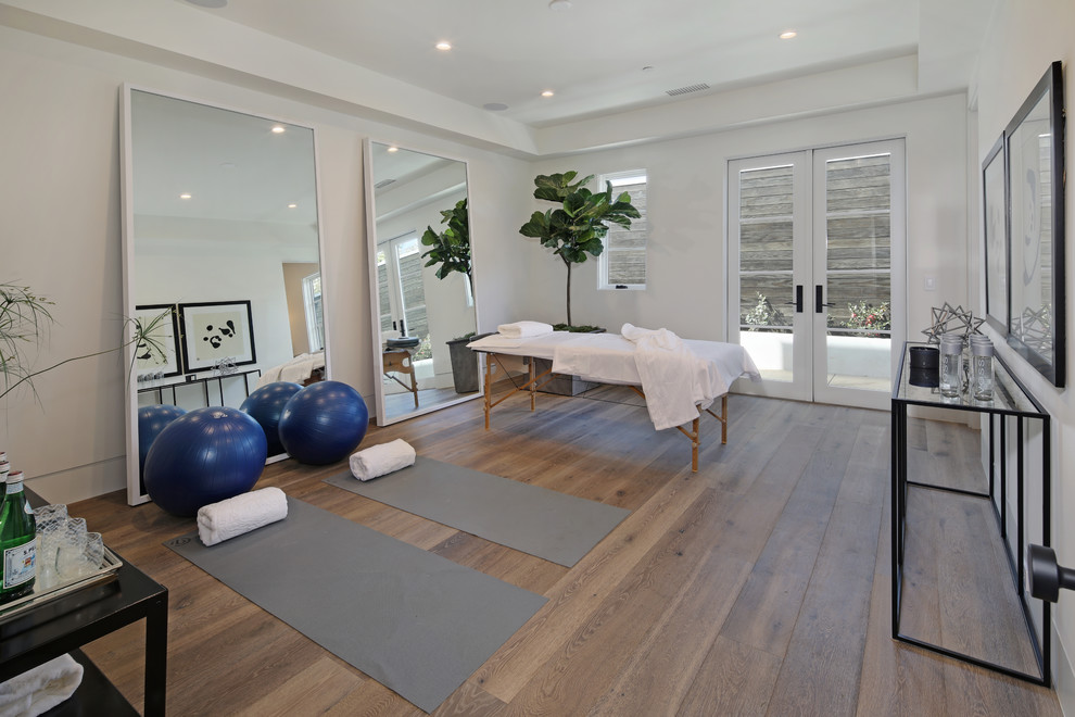Klassischer Yogaraum mit weißer Wandfarbe, braunem Holzboden und braunem Boden in Los Angeles