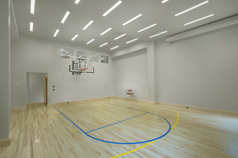 Cette photo montre un terrain de sport intérieur tendance avec un mur gris, parquet clair et un sol beige.