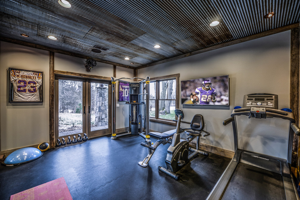 This is an example of a medium sized rustic multi-use home gym in Minneapolis with beige walls and black floors.