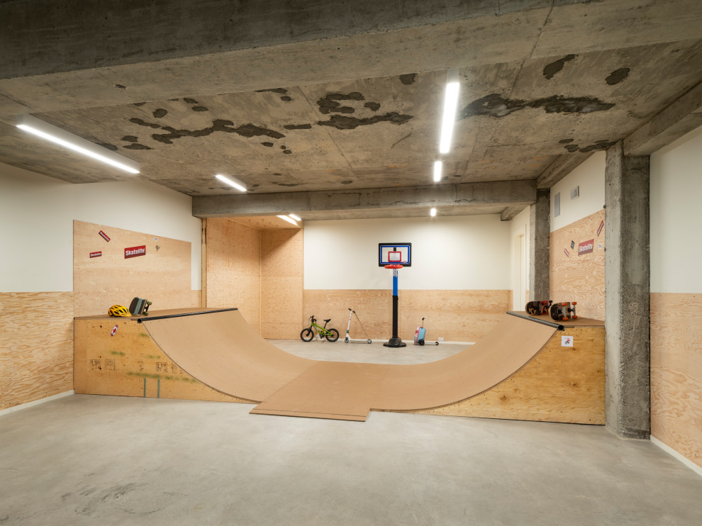 Aménagement d'un terrain de sport intérieur contemporain avec un mur blanc, sol en béton ciré et un sol gris.