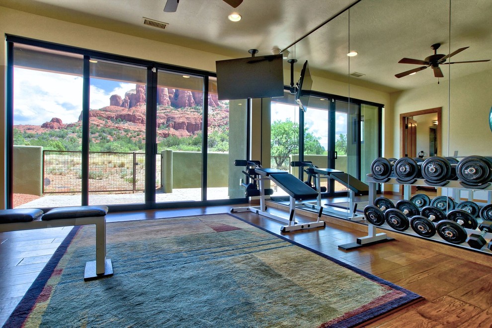 Foto de sala de pesas de estilo americano de tamaño medio con paredes beige y suelo de madera en tonos medios