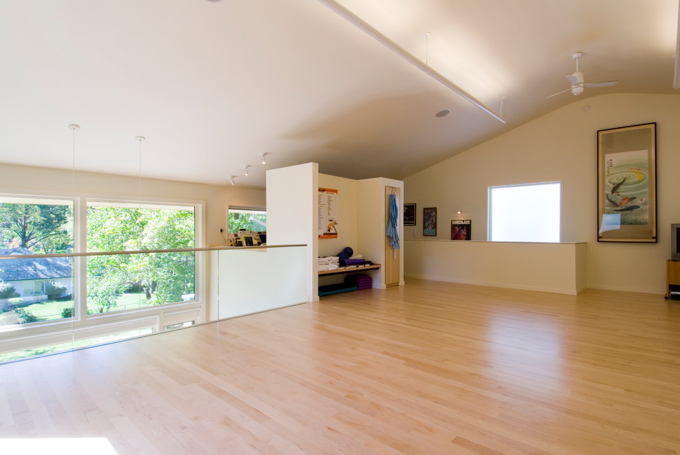 Example of a large trendy light wood floor and beige floor home yoga studio design in Kansas City with white walls