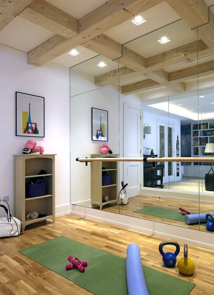 This is an example of a contemporary home gym in London with white walls, medium hardwood flooring, brown floors and a feature wall.