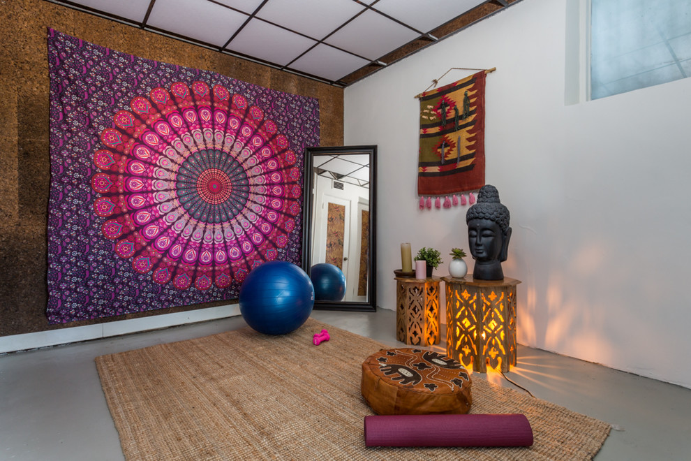 World-inspired home yoga studio in Los Angeles with white walls, concrete flooring, grey floors and a feature wall.