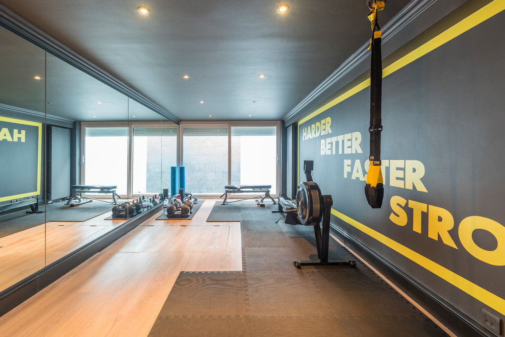 Multifunktionaler, Großer Moderner Fitnessraum mit bunten Wänden, hellem Holzboden und braunem Boden in London