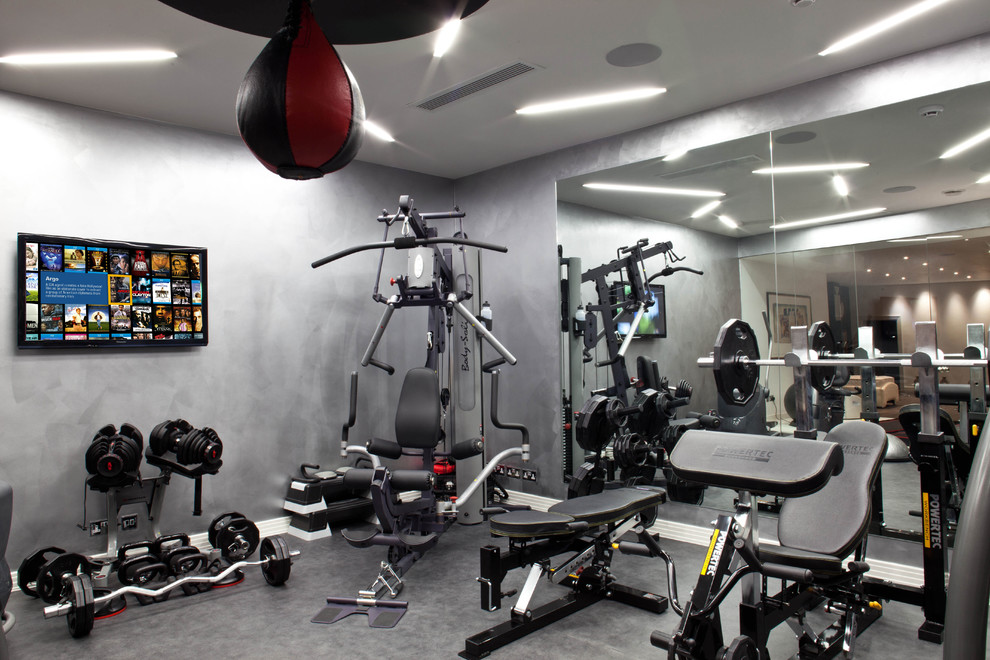Modelo de sala de pesas tradicional renovada de tamaño medio con paredes grises y suelo de linóleo