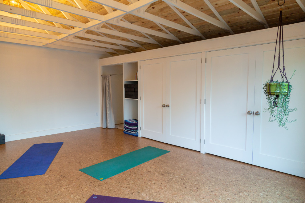 Idée de décoration pour un studio de yoga design de taille moyenne avec un mur blanc, un sol en liège et un sol marron.