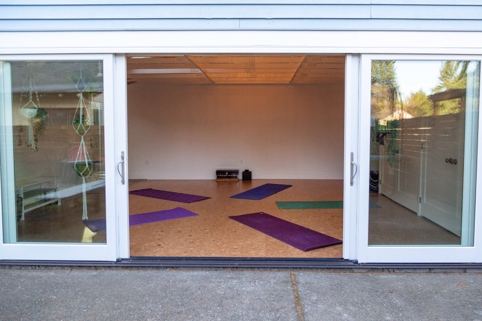 Foto de estudio de yoga actual de tamaño medio con paredes blancas, suelo de corcho y suelo marrón