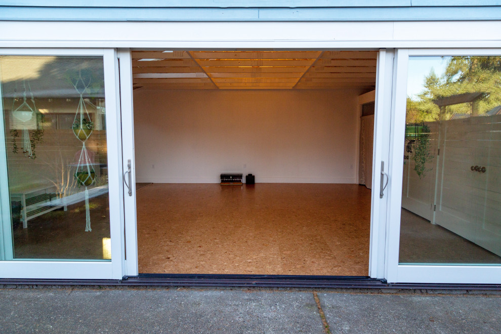 Esempio di uno studio yoga contemporaneo di medie dimensioni con pareti bianche, pavimento in sughero e pavimento marrone