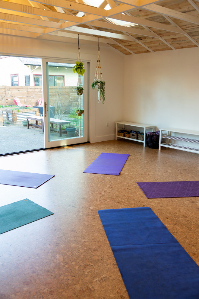 Idee per uno studio yoga minimal di medie dimensioni con pareti bianche, pavimento in sughero e pavimento marrone