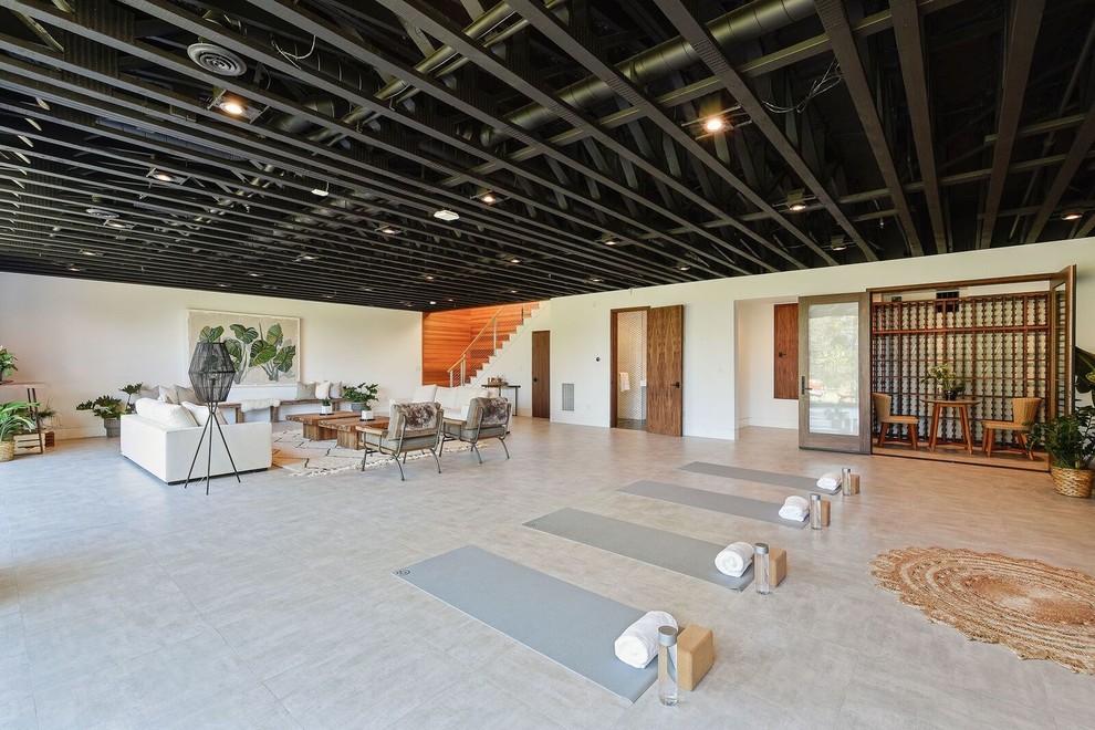 Cette image montre un studio de yoga design avec un mur blanc et un sol gris.