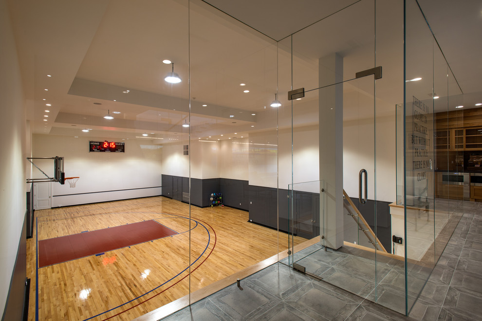 Moderner Fitnessraum mit Indoor-Sportplatz, weißer Wandfarbe und braunem Holzboden in New York