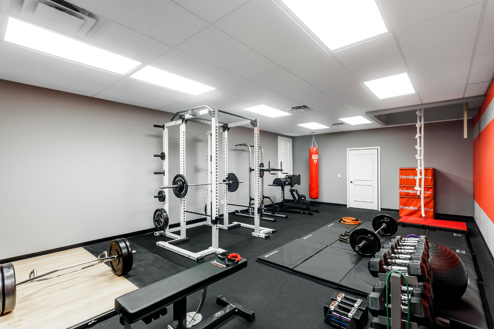 Foto de sala de pesas moderna grande con paredes grises y suelo negro