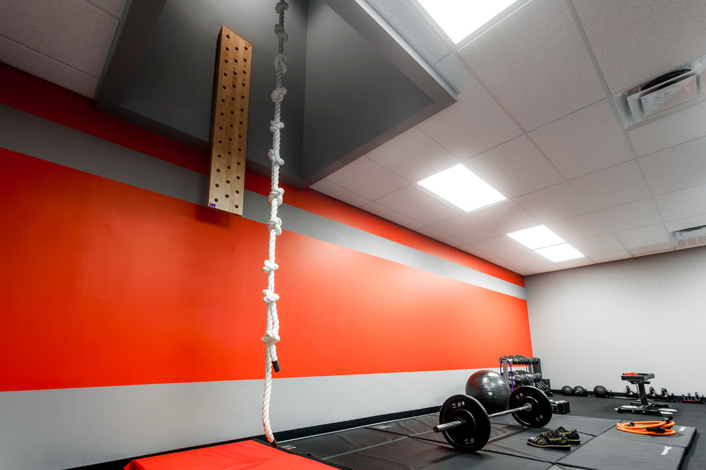 Großer Moderner Fitnessraum mit Kletterwand, roter Wandfarbe und grauem Boden in Orlando