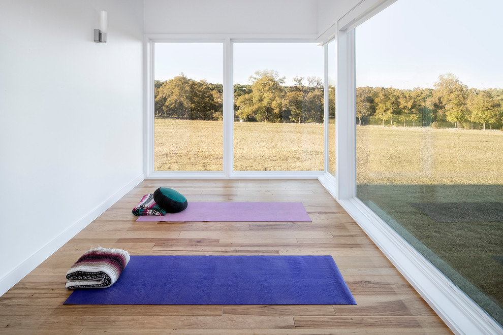 Diseño de estudio de yoga contemporáneo de tamaño medio con paredes blancas, suelo de madera clara y suelo beige