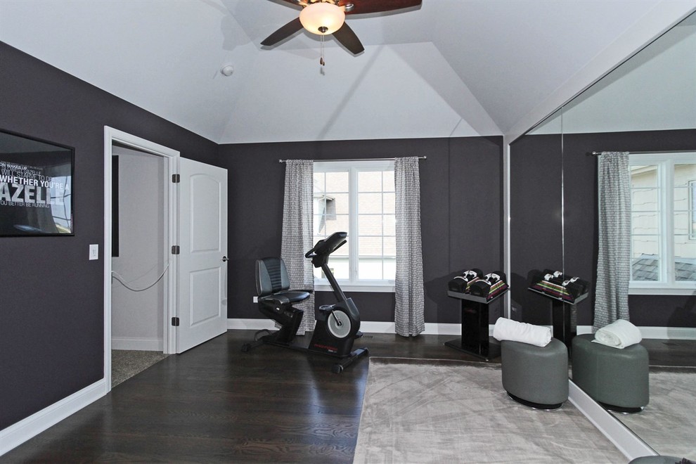Imagen de sala de pesas contemporánea grande con suelo de madera oscura y paredes grises