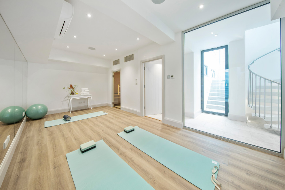 Design ideas for a medium sized contemporary home yoga studio in London with white walls, light hardwood flooring and beige floors.
