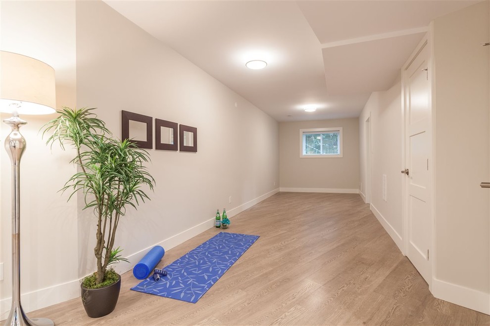 Cette image montre un petit studio de yoga minimaliste avec un mur gris et un sol en bois brun.