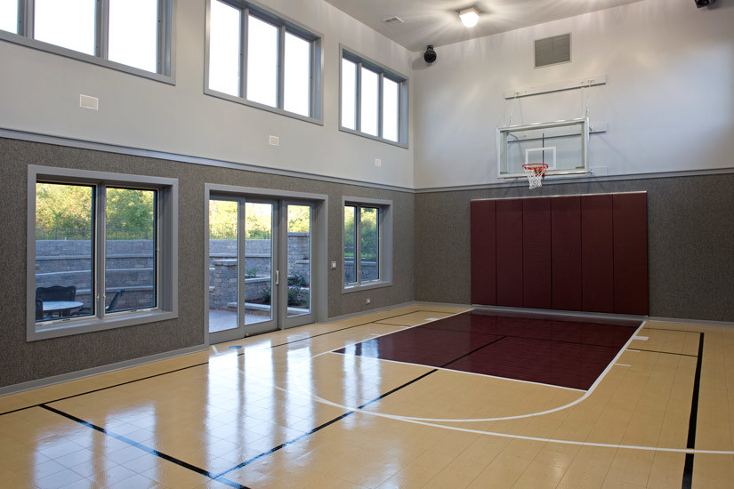 Aménagement d'un grand terrain de sport intérieur avec un mur gris et parquet clair.