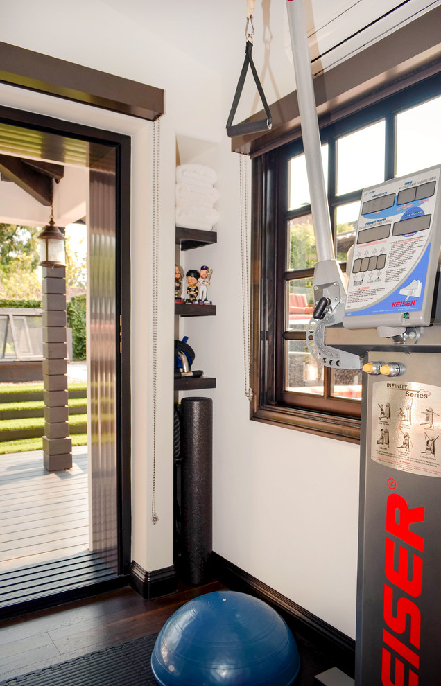 Medium sized mediterranean multi-use home gym in Los Angeles with white walls, laminate floors and brown floors.