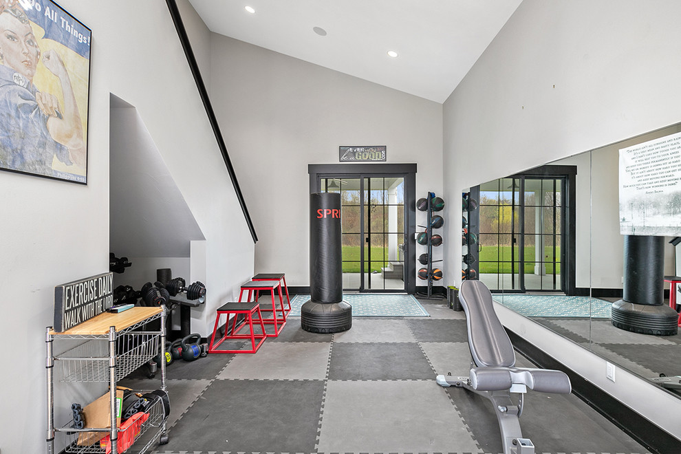 Expansive farmhouse home weight room in Grand Rapids with grey walls and grey floors.