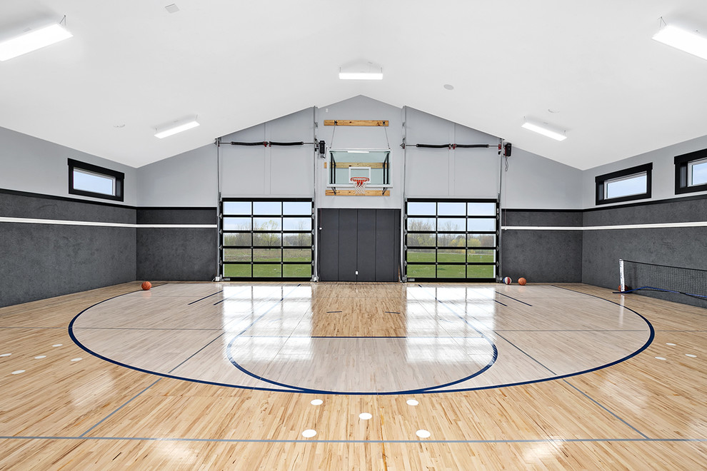 Expansive country indoor sports court in Grand Rapids with grey walls, light hardwood flooring and feature lighting.