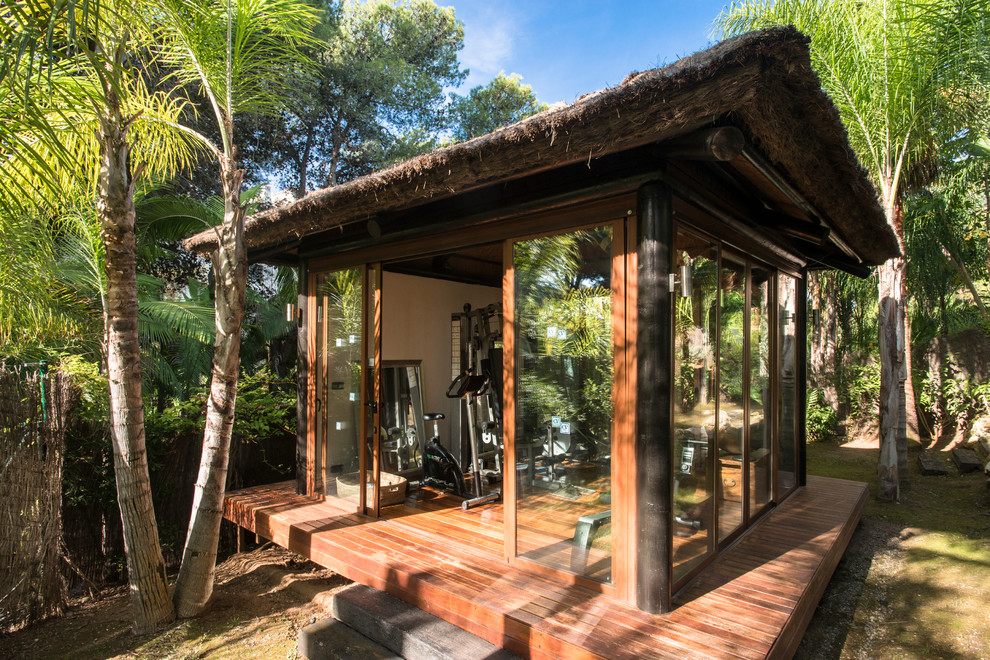 Bild på ett litet tropiskt hemmagym med grovkök, med mellanmörkt trägolv