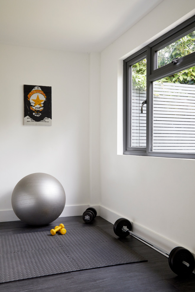 Imagen de sala de pesas clásica renovada de tamaño medio con paredes blancas, suelo vinílico y suelo gris