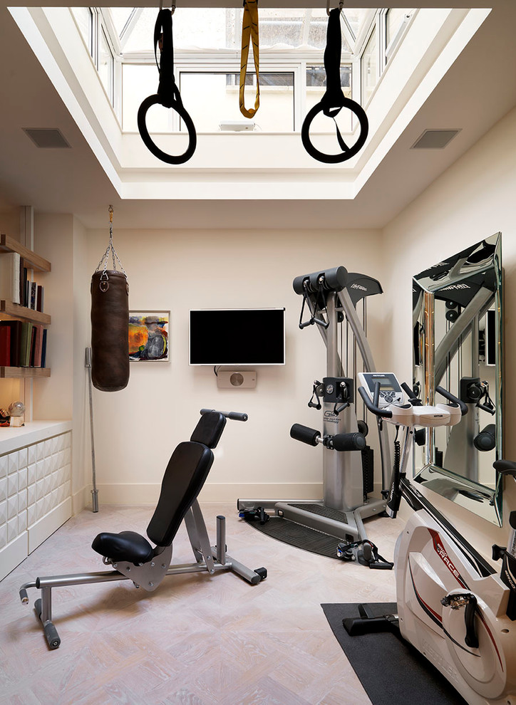 This is an example of a large victorian multi-use home gym in London with white walls and light hardwood flooring.