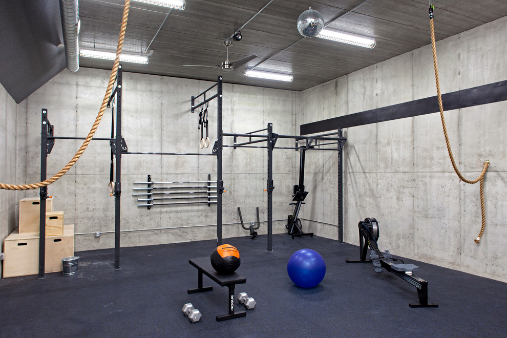 Foto på ett industriellt hemmagym med fria vikter, med grå väggar och blått golv