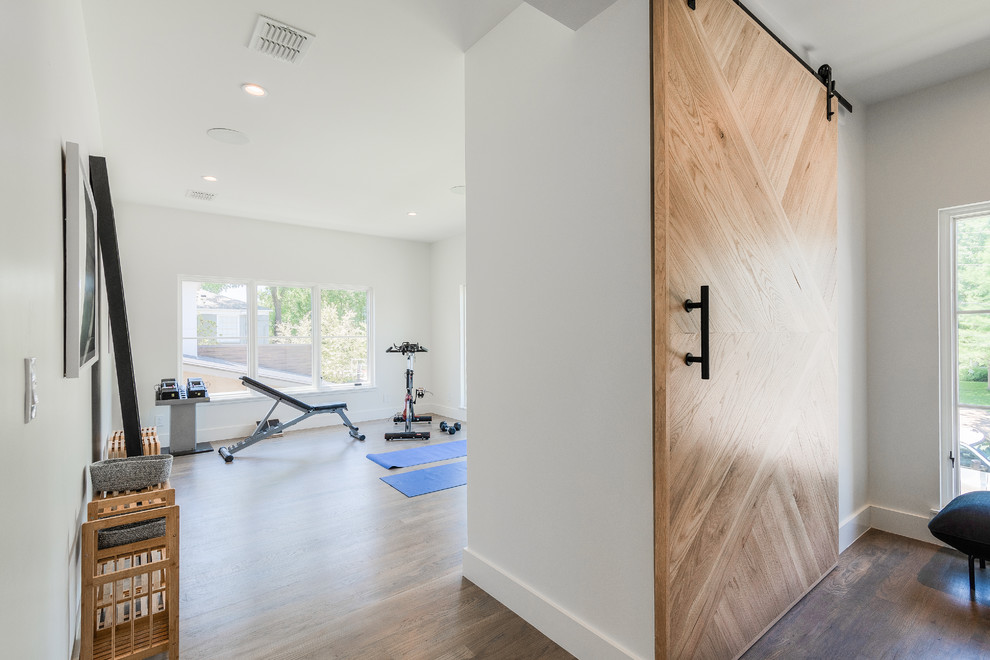 Example of a large trendy light wood floor home yoga studio design in Dallas with white walls