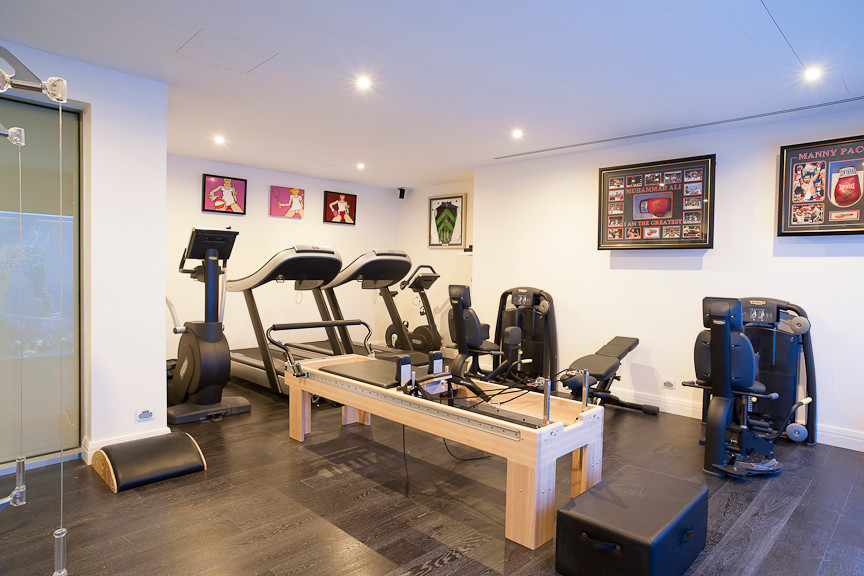 Large contemporary multi-use home gym in Melbourne with white walls and dark hardwood flooring.