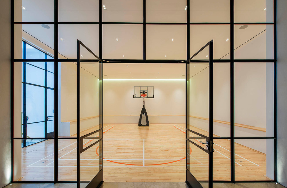 Großer Klassischer Fitnessraum mit Indoor-Sportplatz, weißer Wandfarbe, hellem Holzboden und braunem Boden in London